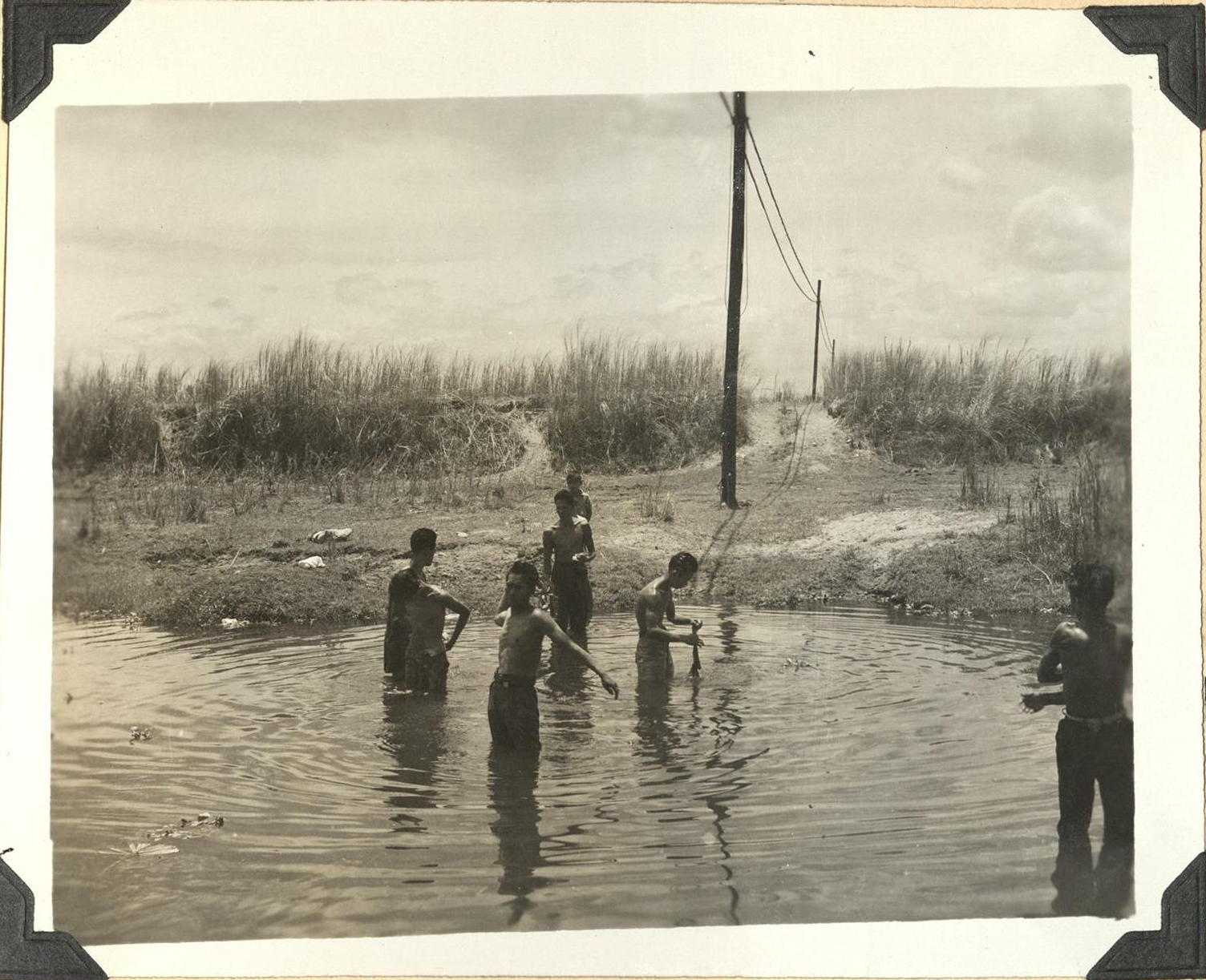 [Untitled – Shirtless men cool off in a river].