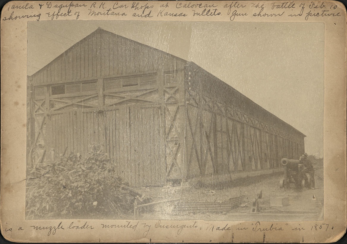 Manila & Dagupan R.R. car shops at Caloocan after the battle of Feb. 10 [1899] showing effect of Montana and Kansas bullets. Gun shown in picture is a muzzle loader mounted by Insurgents. Made in “Trubia” in 1857.