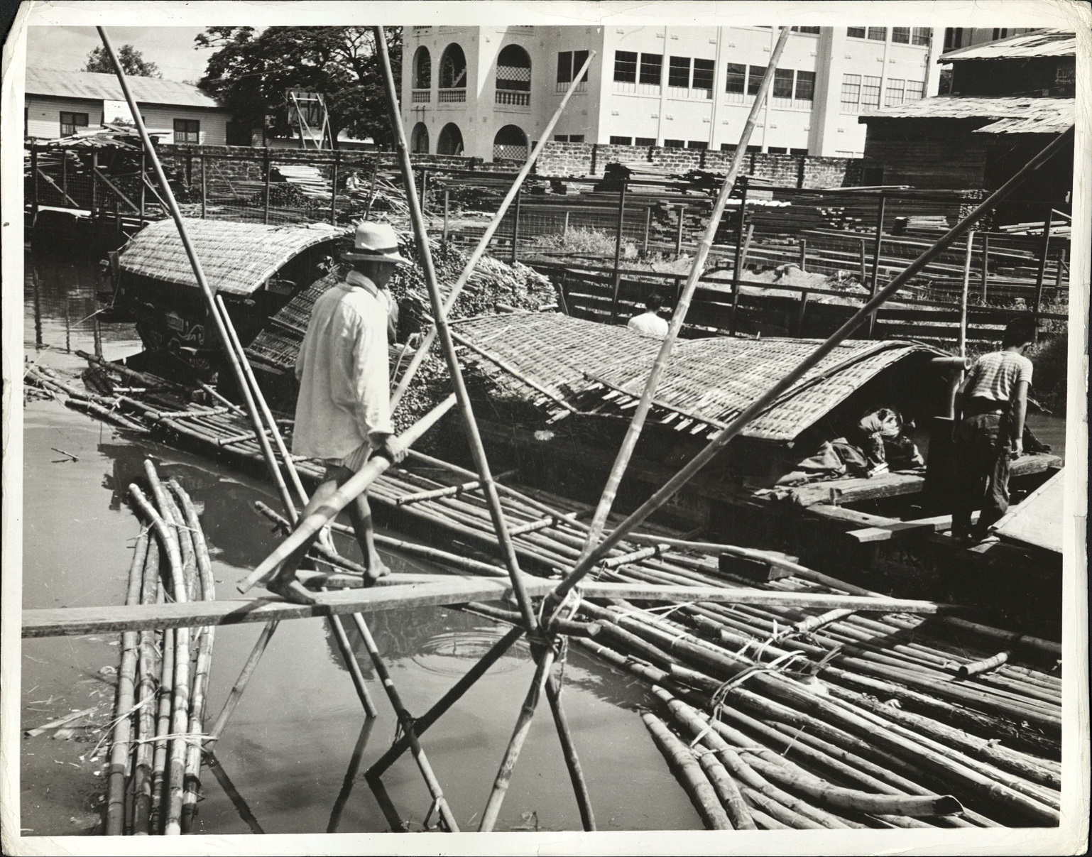 127. PHILIPPINES: Unloading “casco” – boat — at Manila. The casco is a flat-bottomed boat without sail. Two or more men stand on edges and propel boat by the use of bamboo poles. Jacob-1214.