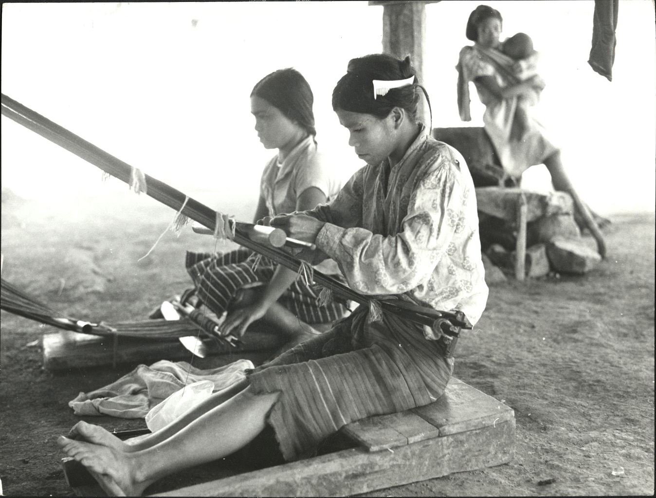 7. PHILIPPINES: Island of Luzon. Women of the Ifugao tribe weaving beneath their huts in a village of mountain farmers north of Manila in the Mountain Province. Sammer 9980.