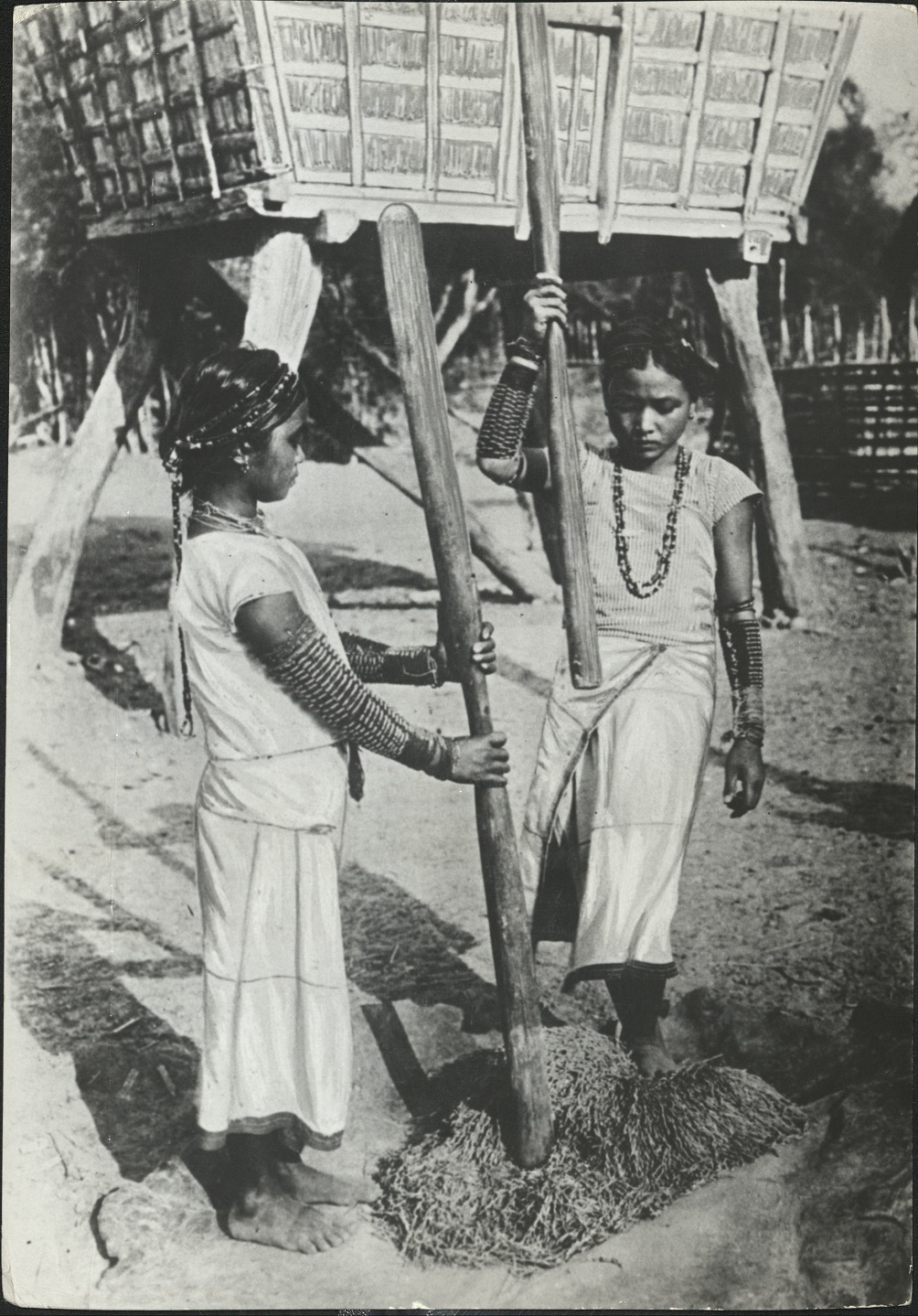 Two young Filipino girls pounding rice. (…)