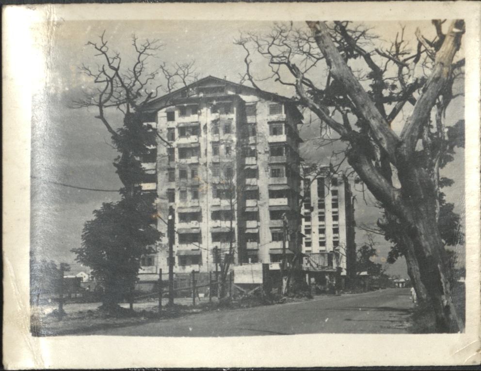 [Untitled – War-damaged Peralta Apartments with Bay View Hotel in background].