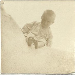 [Untitled – Small child sits on a big rock].