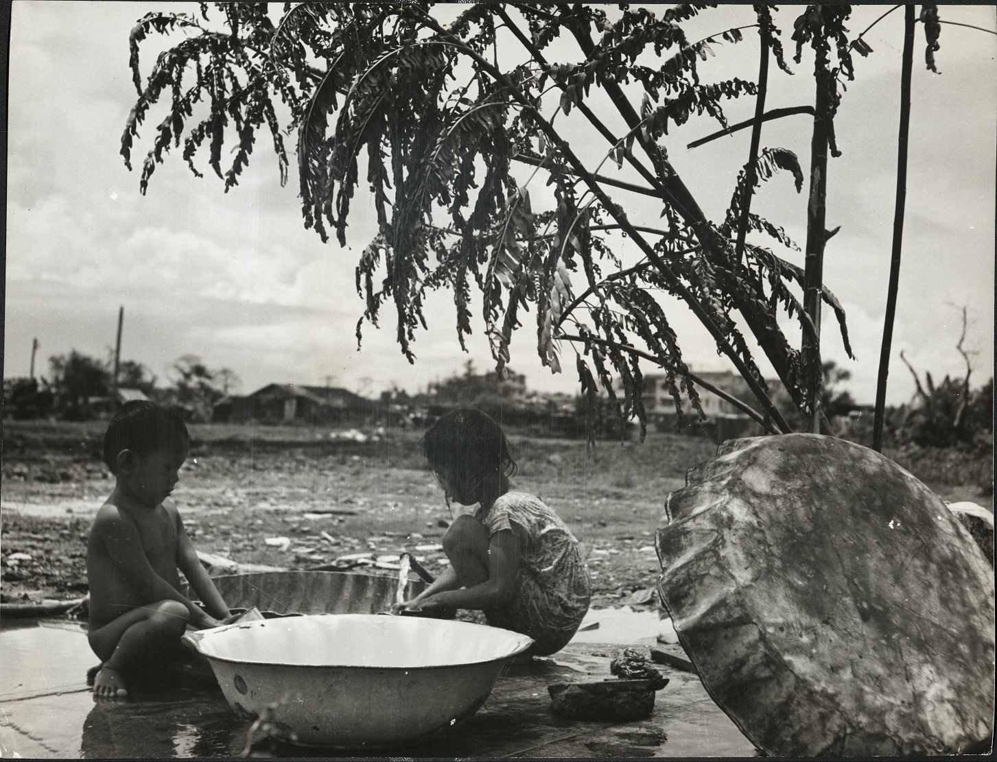 24. PHILIPPINES – Children. Manila children play while the family wash gets the attention of their mother.  J-1436.