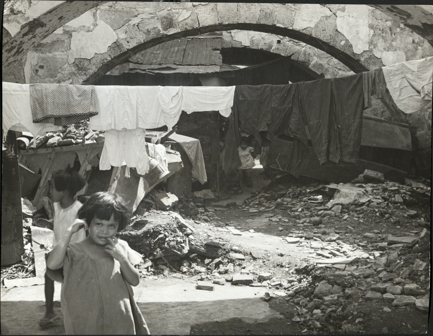 30. PHILIPPINES – Manila. Children play in the shadows of bombed-out Manila buildings.  J-1441.