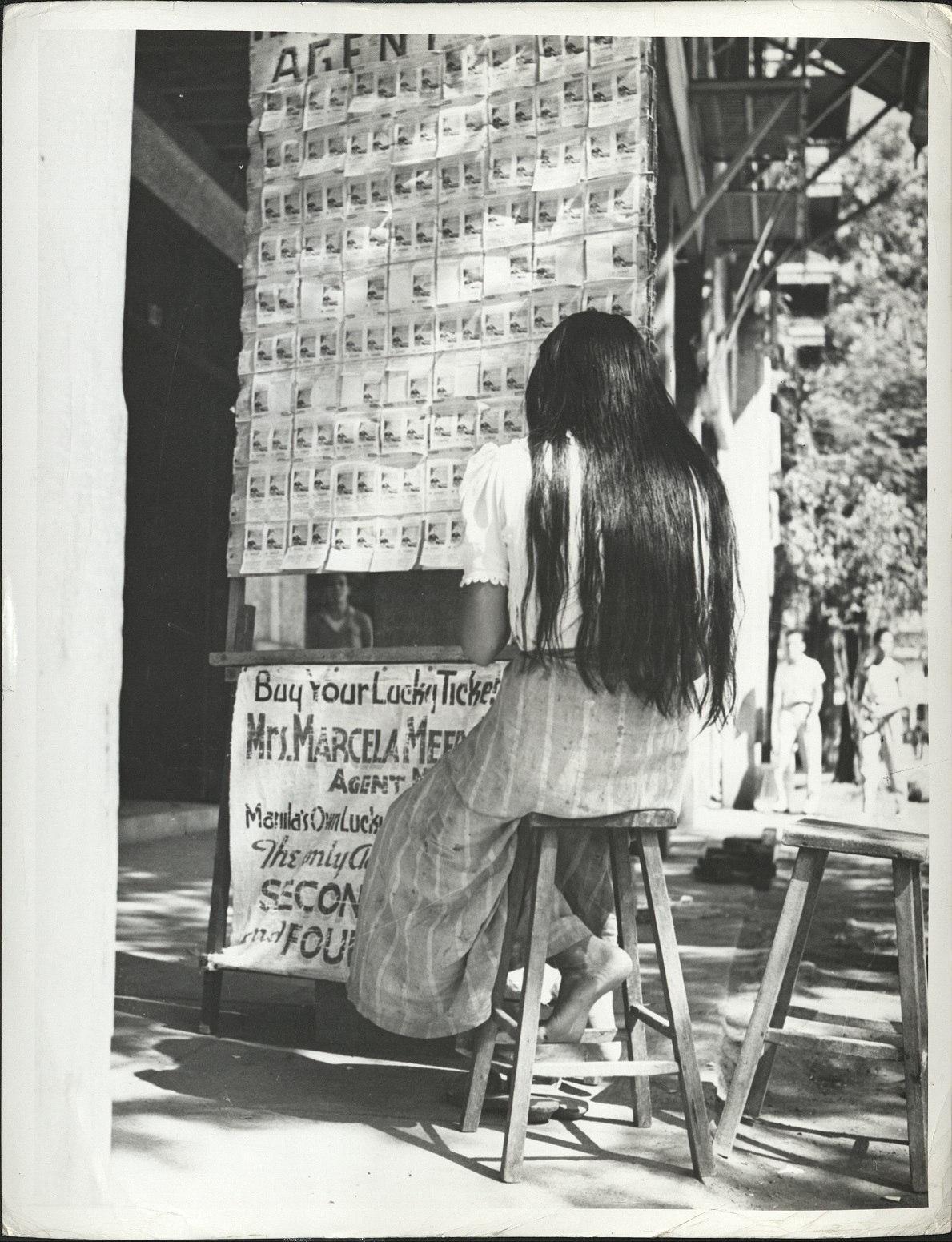 322. PHILIPPINES: The agent of a lottery booth in Manila sells tickets for the Government sponsored sweepstakes, the profits of which go to build playgrounds and toward public charities.