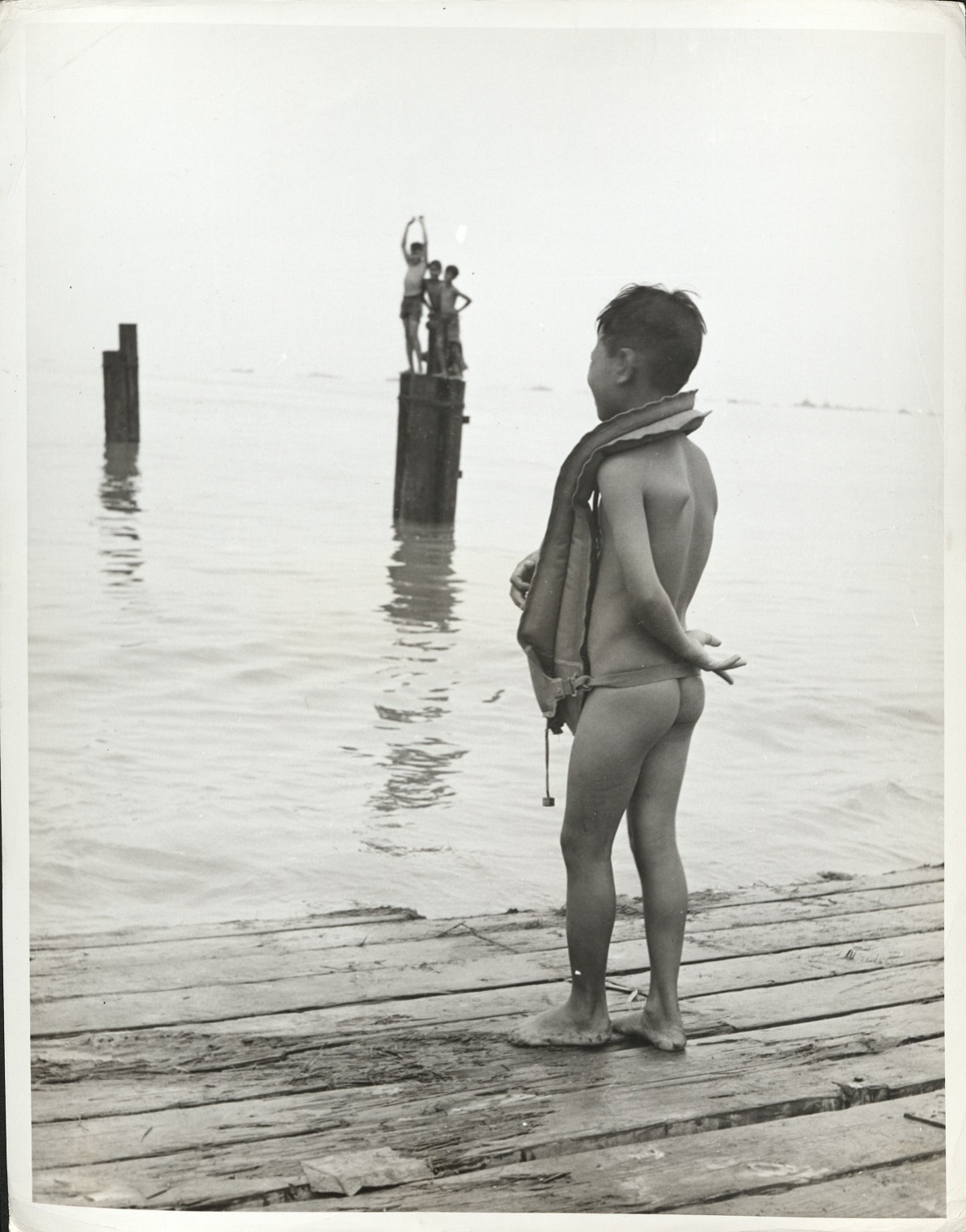 [Caption missing – Filipino boy wearing life preserver on dock].