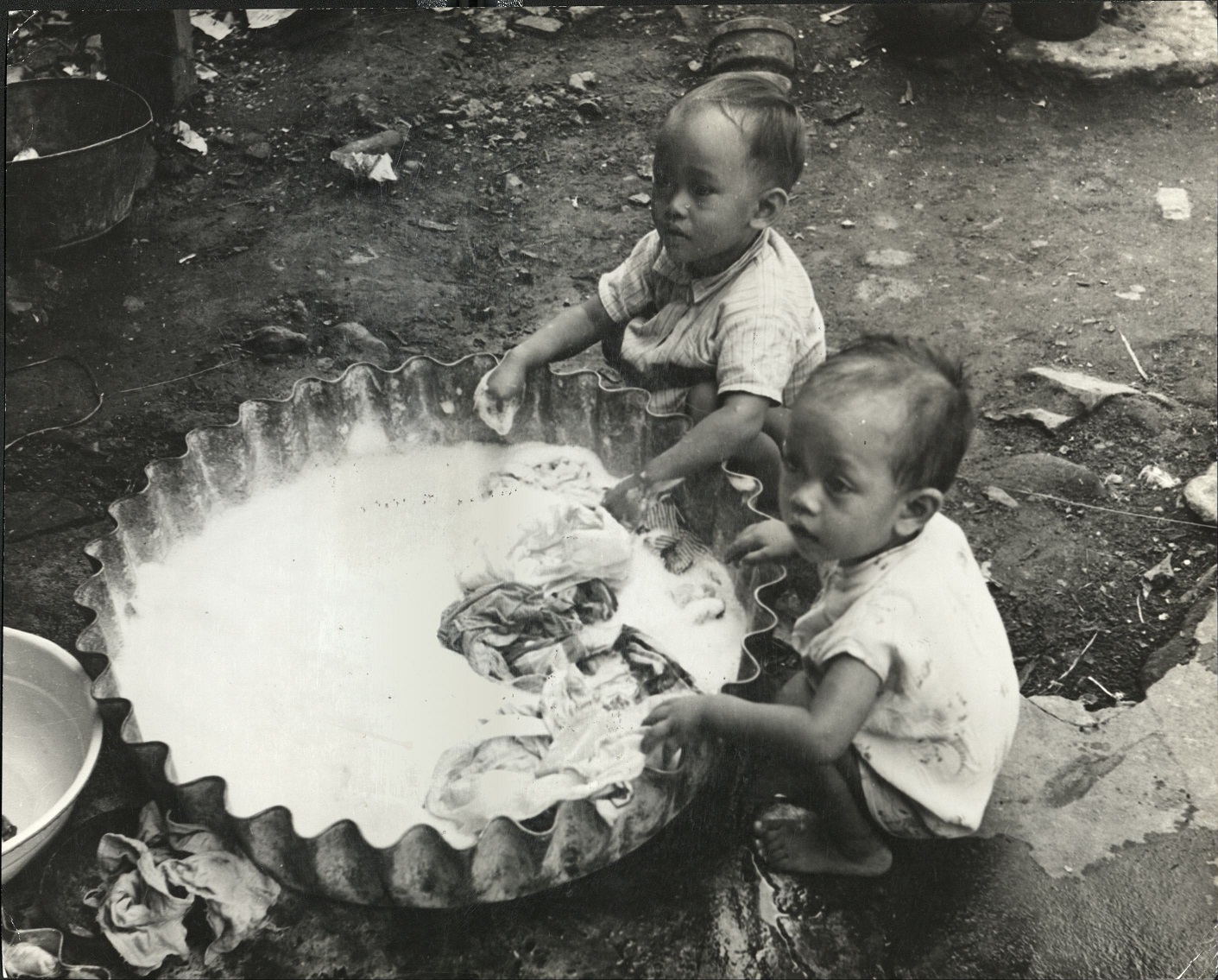 126. PHILIPPINES: Wash day. Children play near zinc wash basin, known as “batya.”