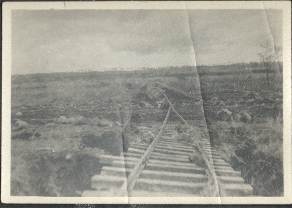 [Untitled – Twisted and broken railroad tracks and ties vanish into a morass of dirt and rocks after a flood or landslide].
