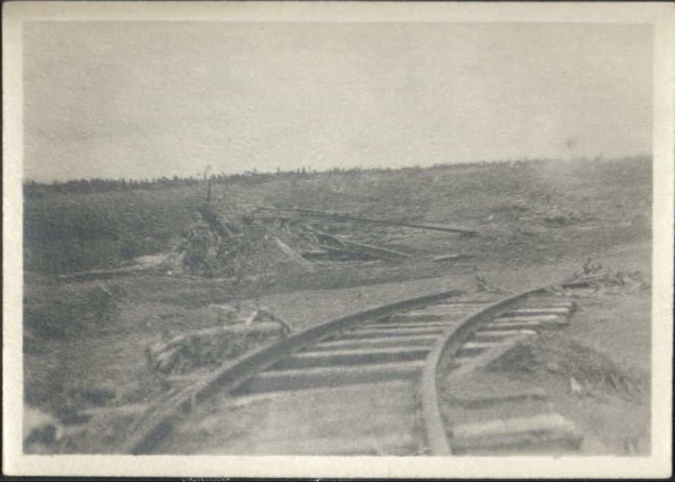 [Untitled – Washed-out bridge and  railroad tracks covered with dirt and rocks after a flood or landslide].