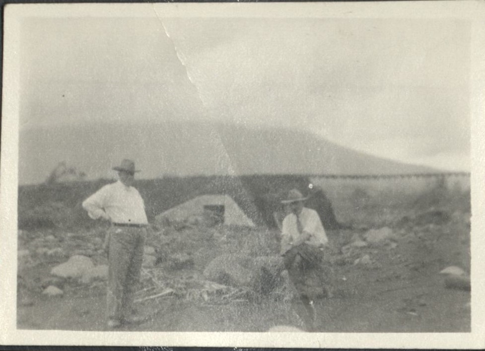 [Untitled – Two men pose near ruined  railroad tracks and washed-out bridge after a flood or landslide].
