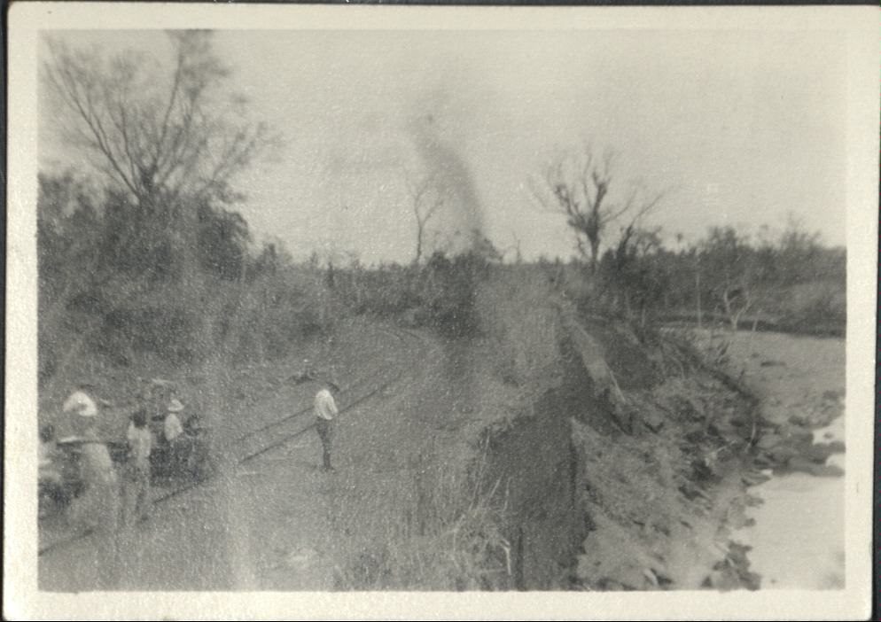 [Untitled – Men inspect railroad tracks barely missed by flood or landslide erosion].