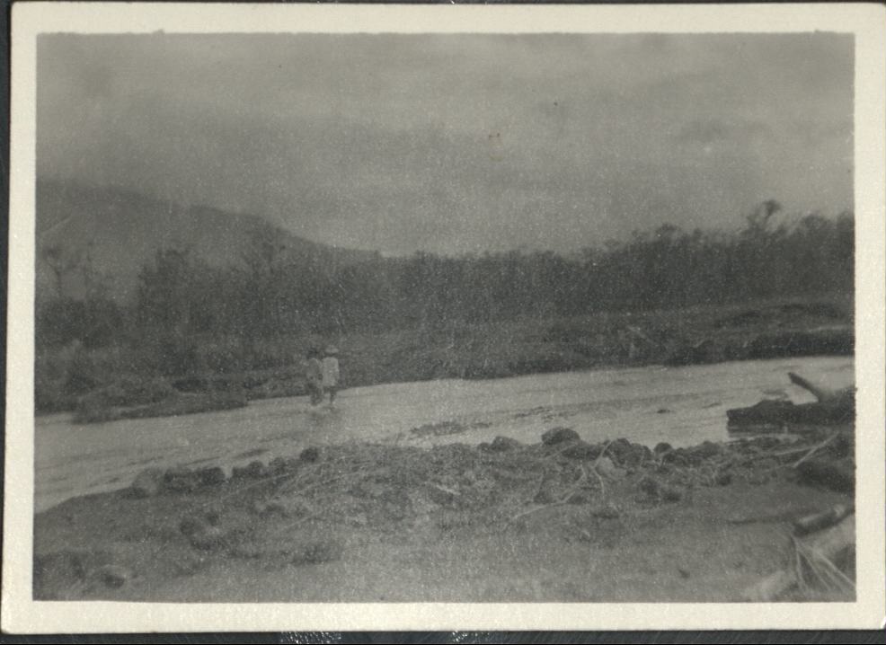 [Untitled – Men wade in stream with dirt and rocks after a flood or landslide].