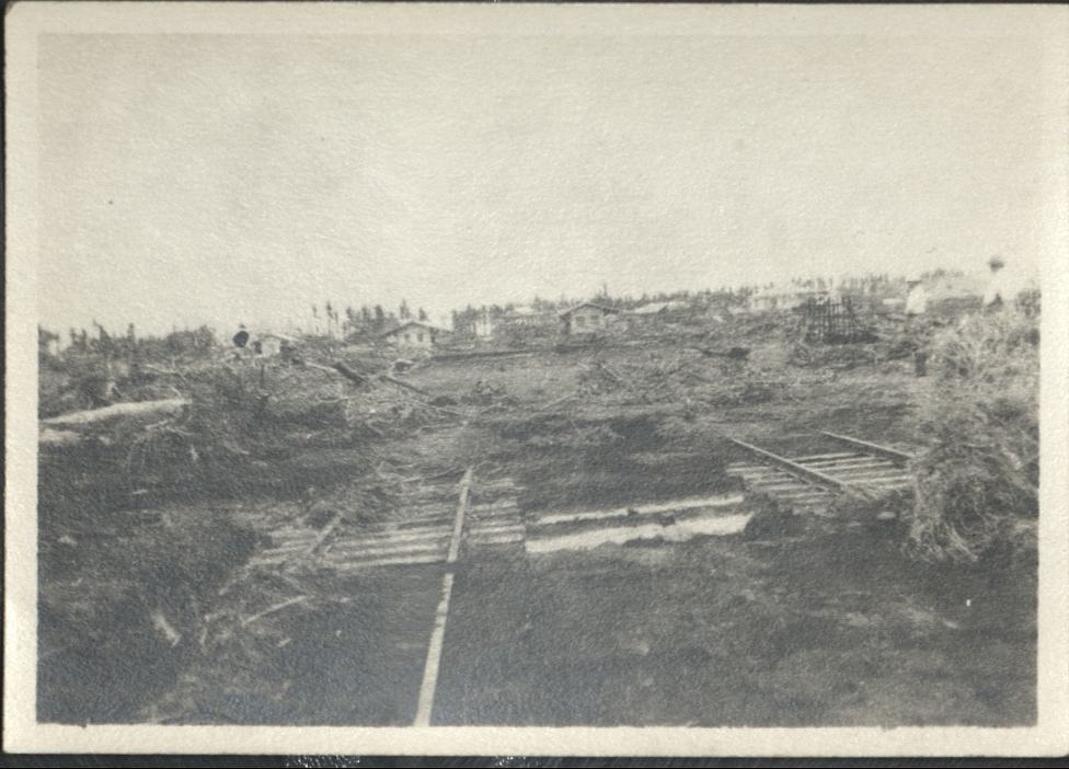 [Untitled – Two sets of washed-out railroad tracks lie amid mud and trees after a flood or landslide].