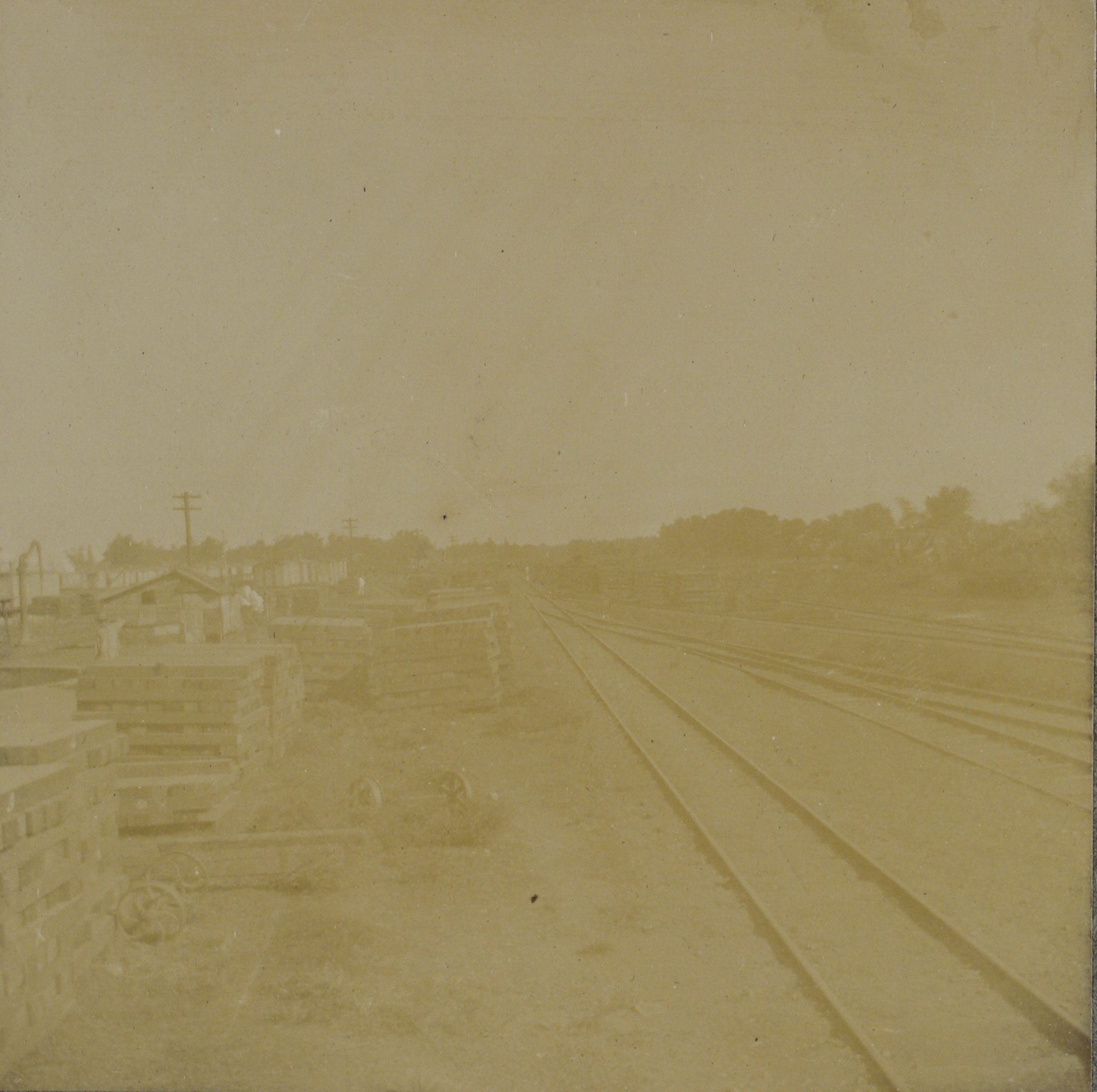 [Untitled – Railroad tracks with ties stacked alongside].