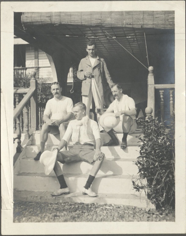 [Untitled – Four expatriate men relax on porch stairs].