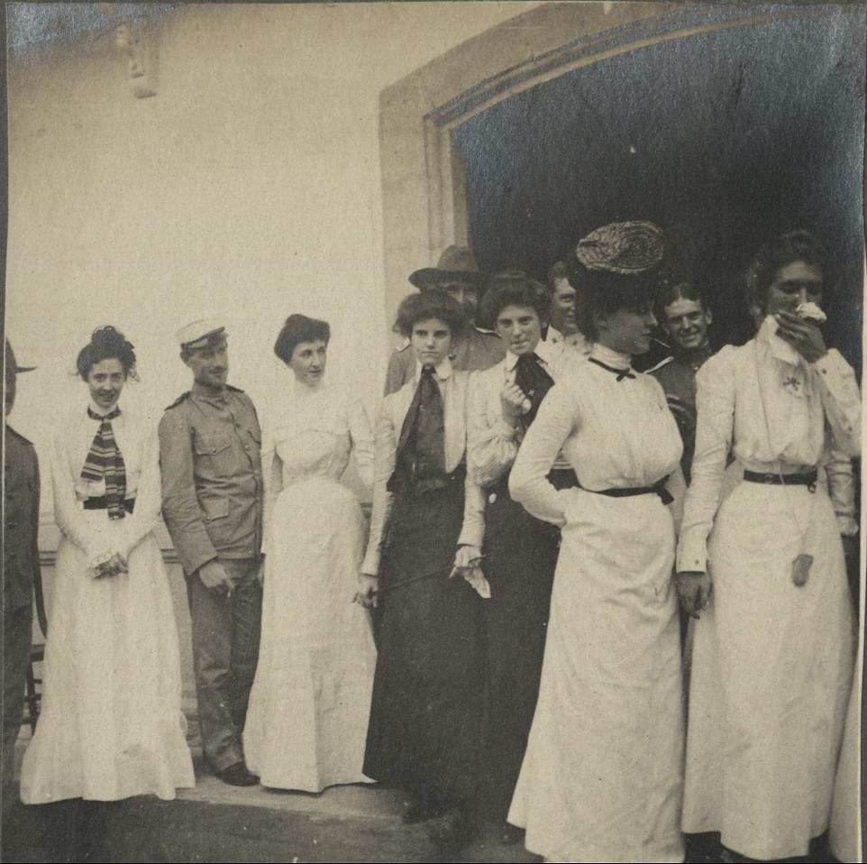 [Untitled -Group of expatriates, mostly women, under house eaves].