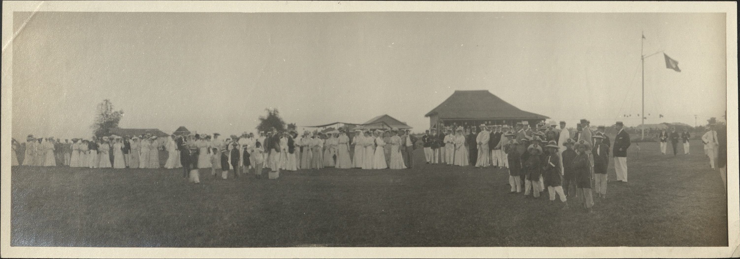 [Untitled – Expatriates watching a ceremony or performance outdoors in a big field].