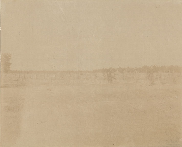 [Untitled – Two U.S. soldiers stand next to bamboo fence in a field].