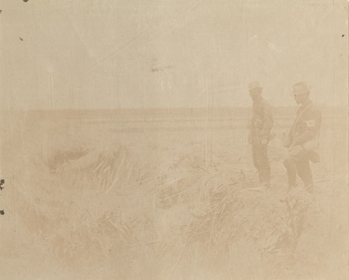 [Untitled – Two U.S. soldiers – one a medic – look into a battlefield trench].