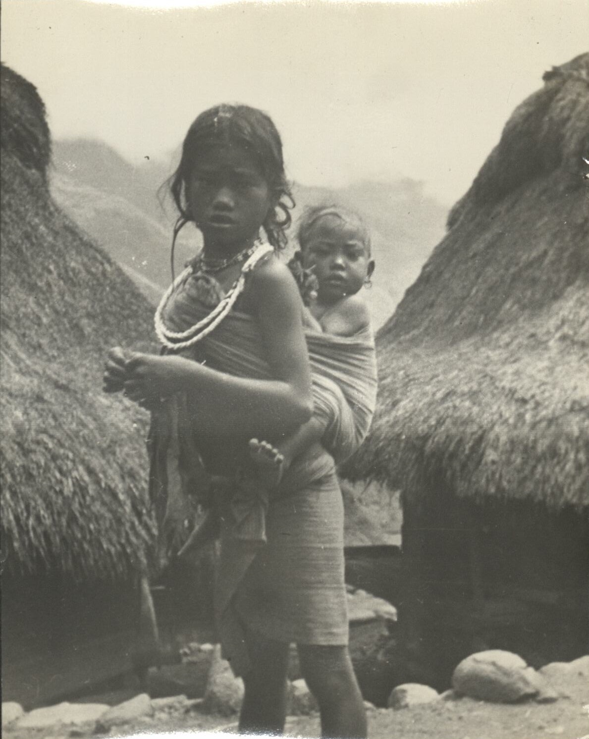 A young Igorot girl carrying her sister.