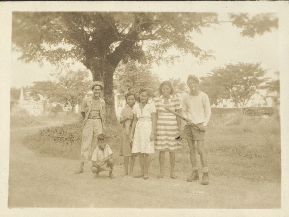 Manila’s “Chinese” Cemetery [Filipinos with a bat pose in cemetery].
