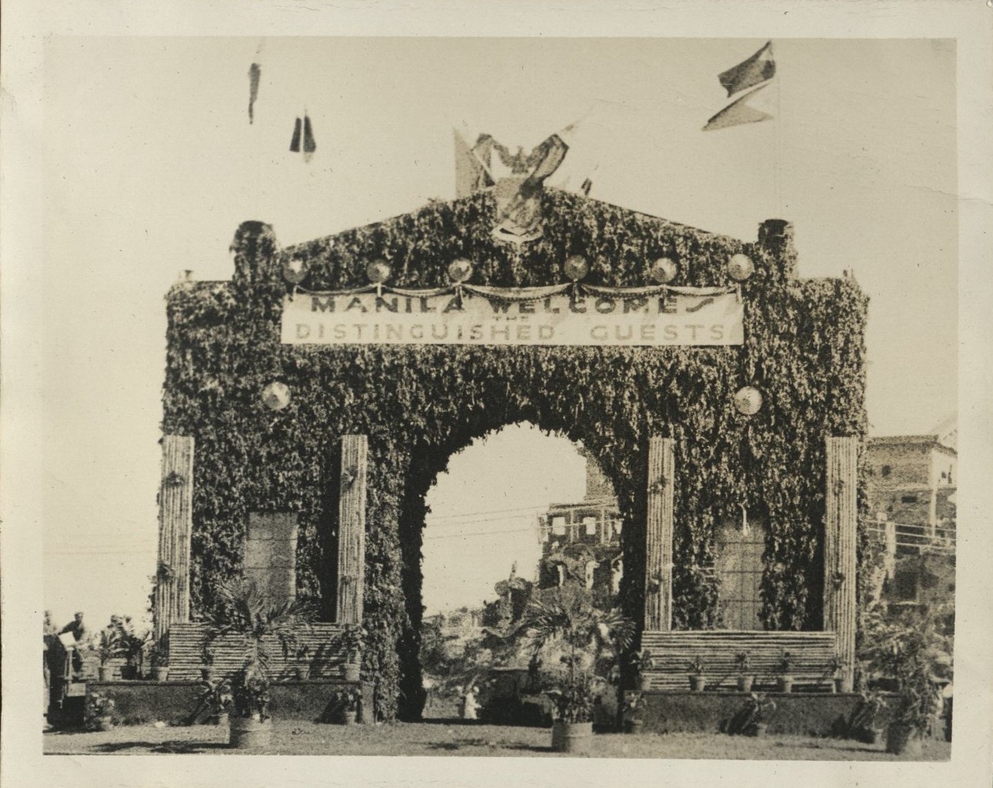 [Untitled – Decorated arch by Legislative Building ruins: “Manila welcomes distinguished guests”].