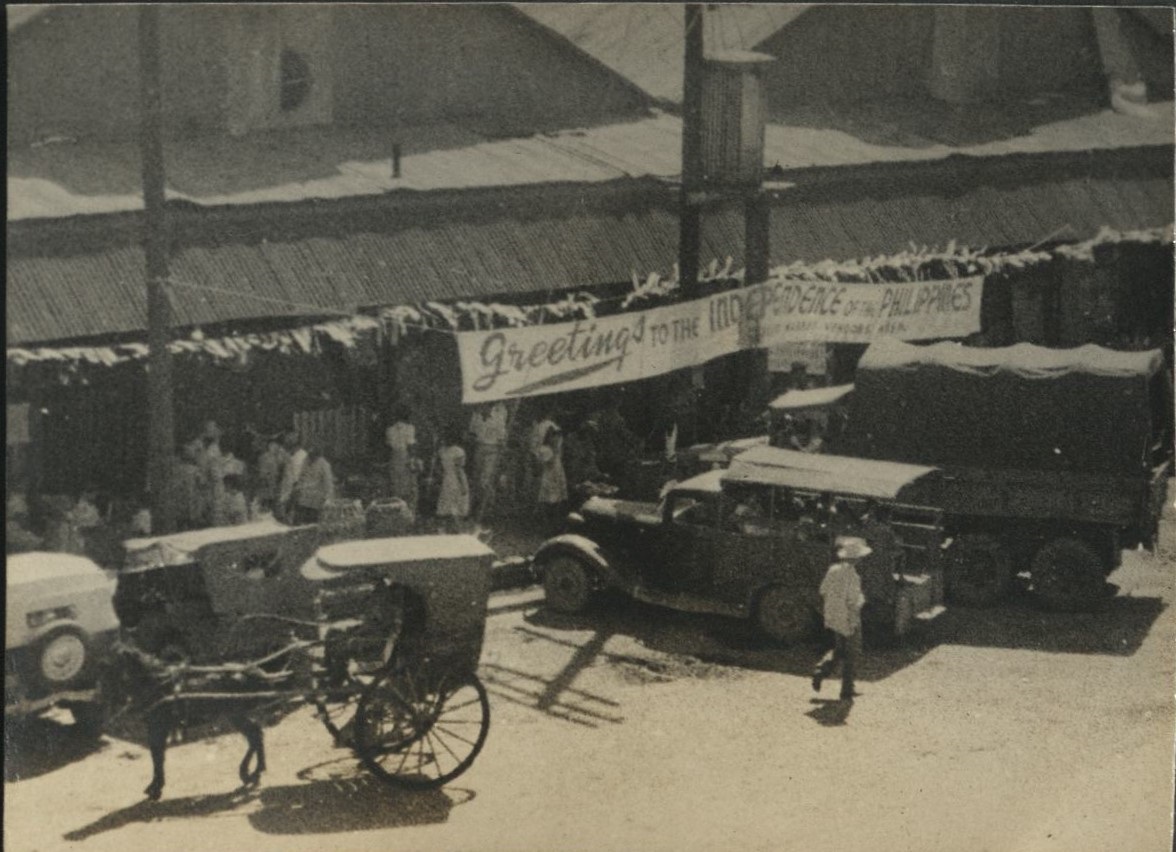 [Untitled – Manila street scene and banner: “Greetings to the Independence of the Philippines”].