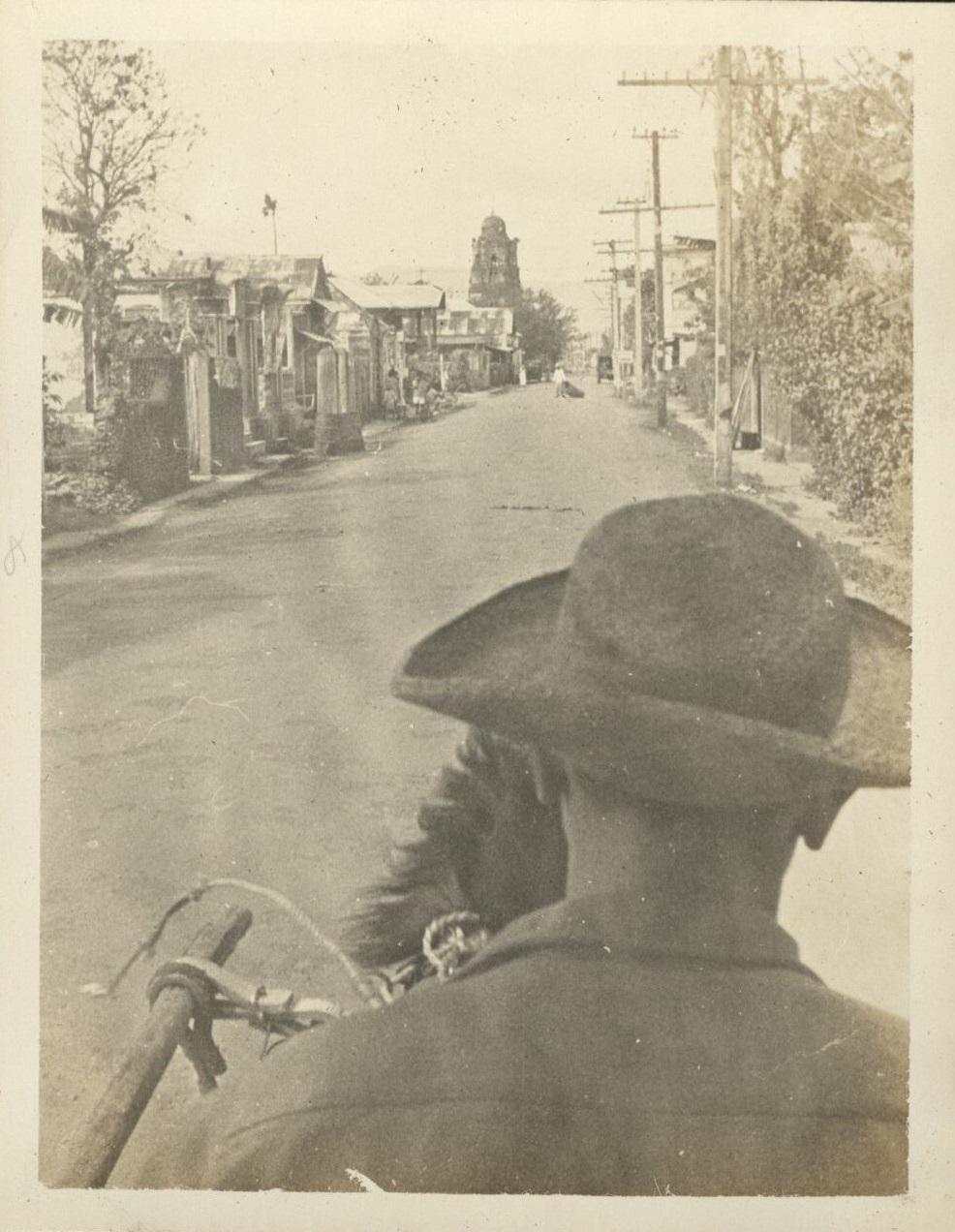 [Untitled – Looking over a cochero’s shoulder down a street with a bell tower].
