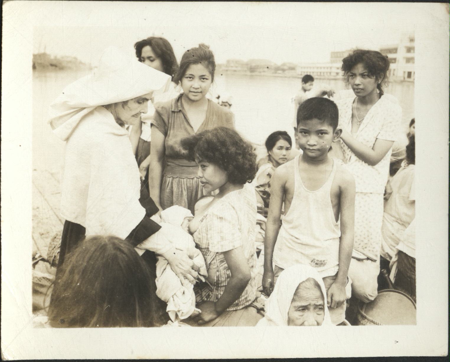 [Untitled – Manila during liberation: Civilian refugees at the Pasig River somehow find the strength to smile, February 1945].