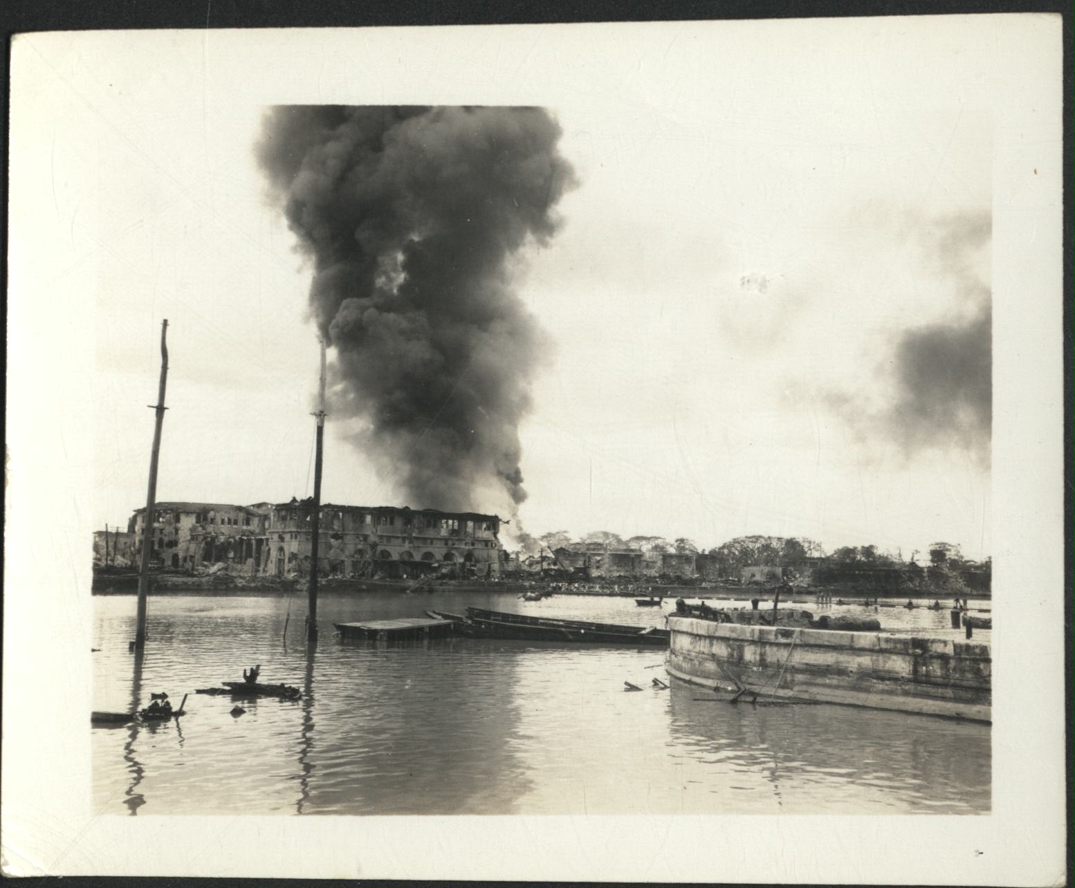 [Untitled – Fire and destruction in Manila during liberation: Fire burns behind destroyed building by Pasig River, February 1945].