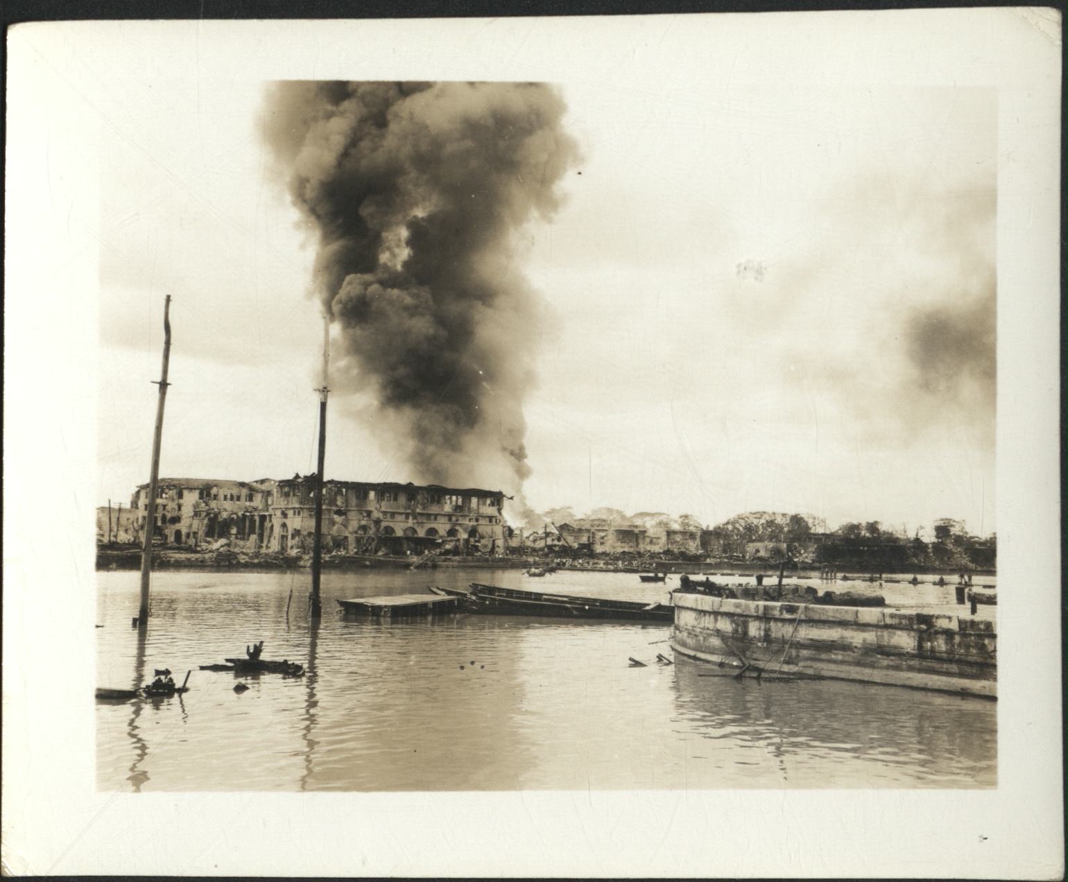 [Untitled – Fire and destruction in Manila during liberation: Fire burns behind destroyed building by Pasig River, February 1945].