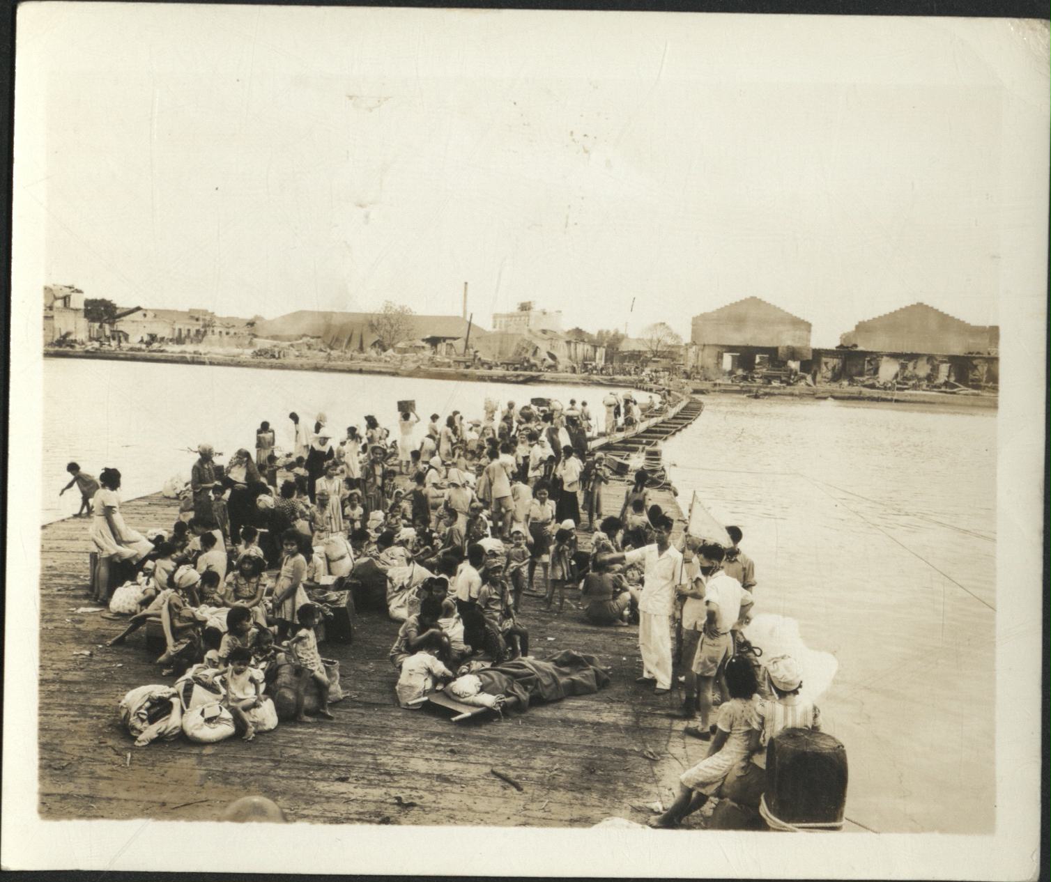 [Untitled – Manila during liberation: Civilian refugees gather at dock by a pontoon footbridge across Pasig River, February 1945].