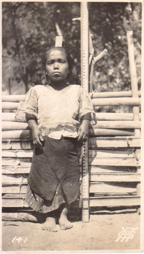 141. [Untitled – A short Filipina stands next to a measuring stick].