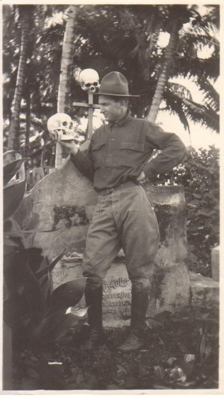 [Untitled – Man, possibly Leavitt W. Thurlow, holding a human skull next to a monument].
