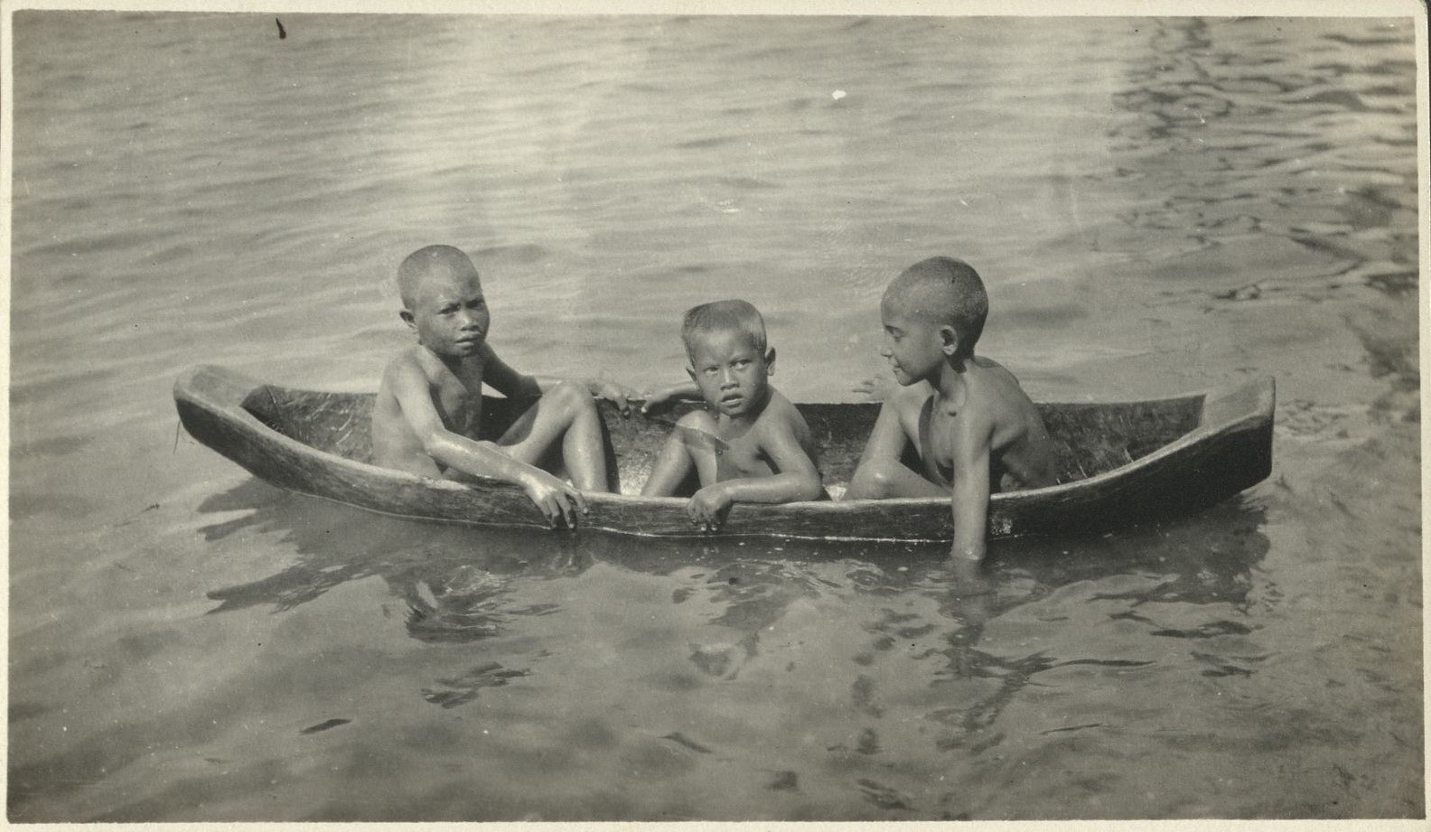 [Untitled – Three young Filipino boys on a river in a tiny dugout canoe].
