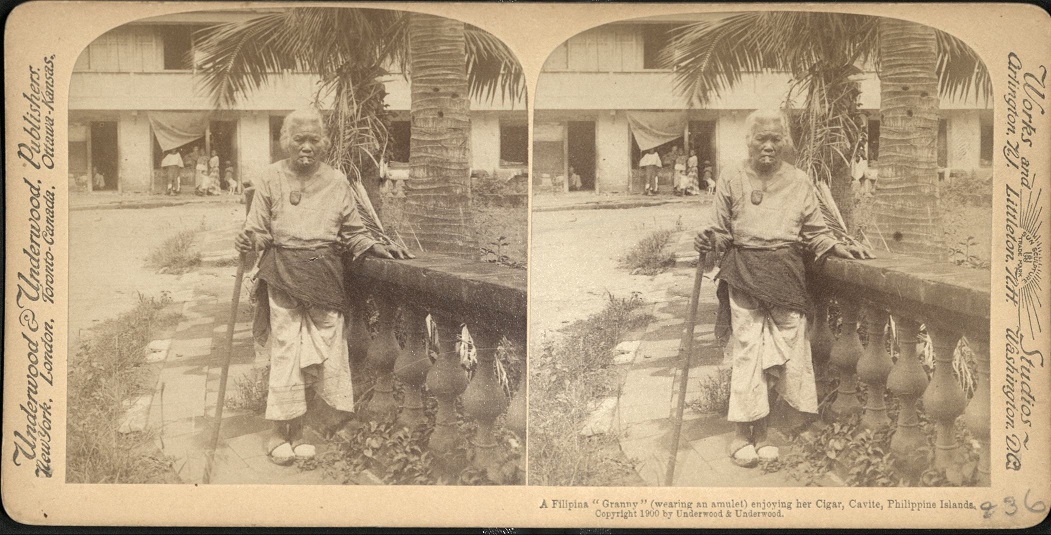 A Filipina “Granny” (wearing an amulet) enjoying her Cigar, Cavite, Philippine Islands.